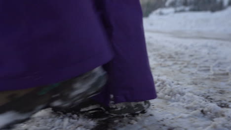 close up of legs in winter boots walking on slippery icy road in snowy winter landscape of mountain, full frame