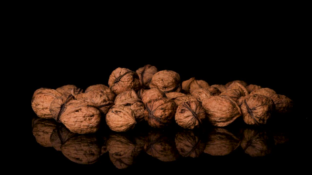 Walnuts Falling Into a Pile of More Walnuts, Black Background