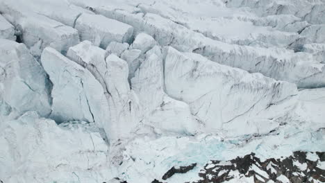 aerial top down view of the crevasses on the edge of a large glacier on a sunny day in winter in the alps