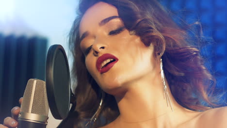 Beautiful woman sings a song in a professional recording studio. Slow motion