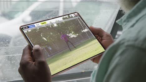 Video-of-person-sitting-on-the-couch-and-watching-football-match-on-tablet