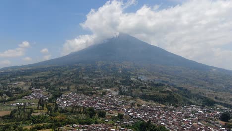 small township and massive mount sumbing in background, aerial drone view