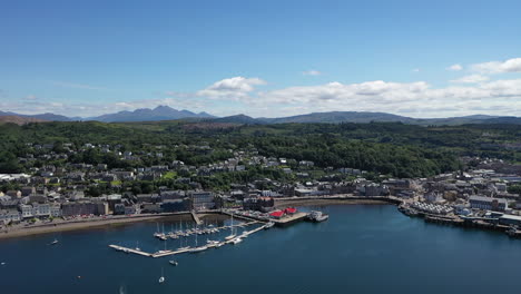 hermosa toma de drones de oban, escocia, panorámica a lo largo de toda la costa de la ciudad, revelando el mar y las montañas a su alrededor