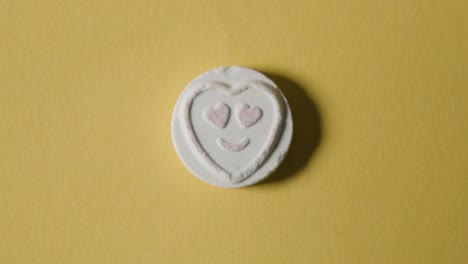 caramelo de corazón con amor emoji sobre fondo amarillo