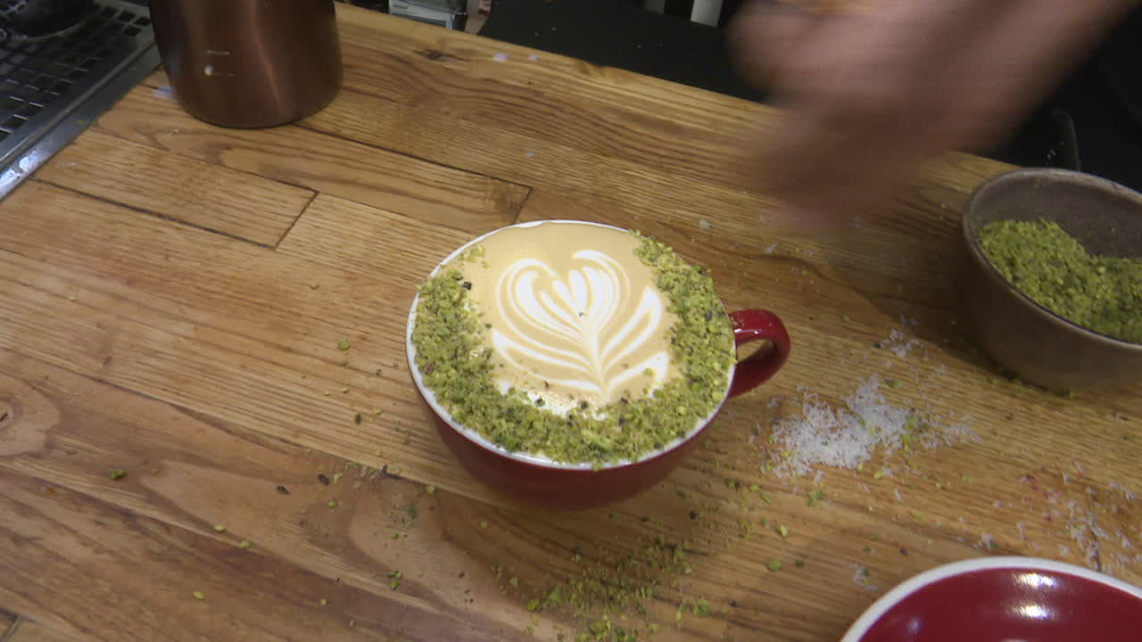 Barista creating a pistachio-sprinkled latte art