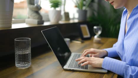 persona de negocios irreconocible escribiendo en el teclado de la computadora portátil