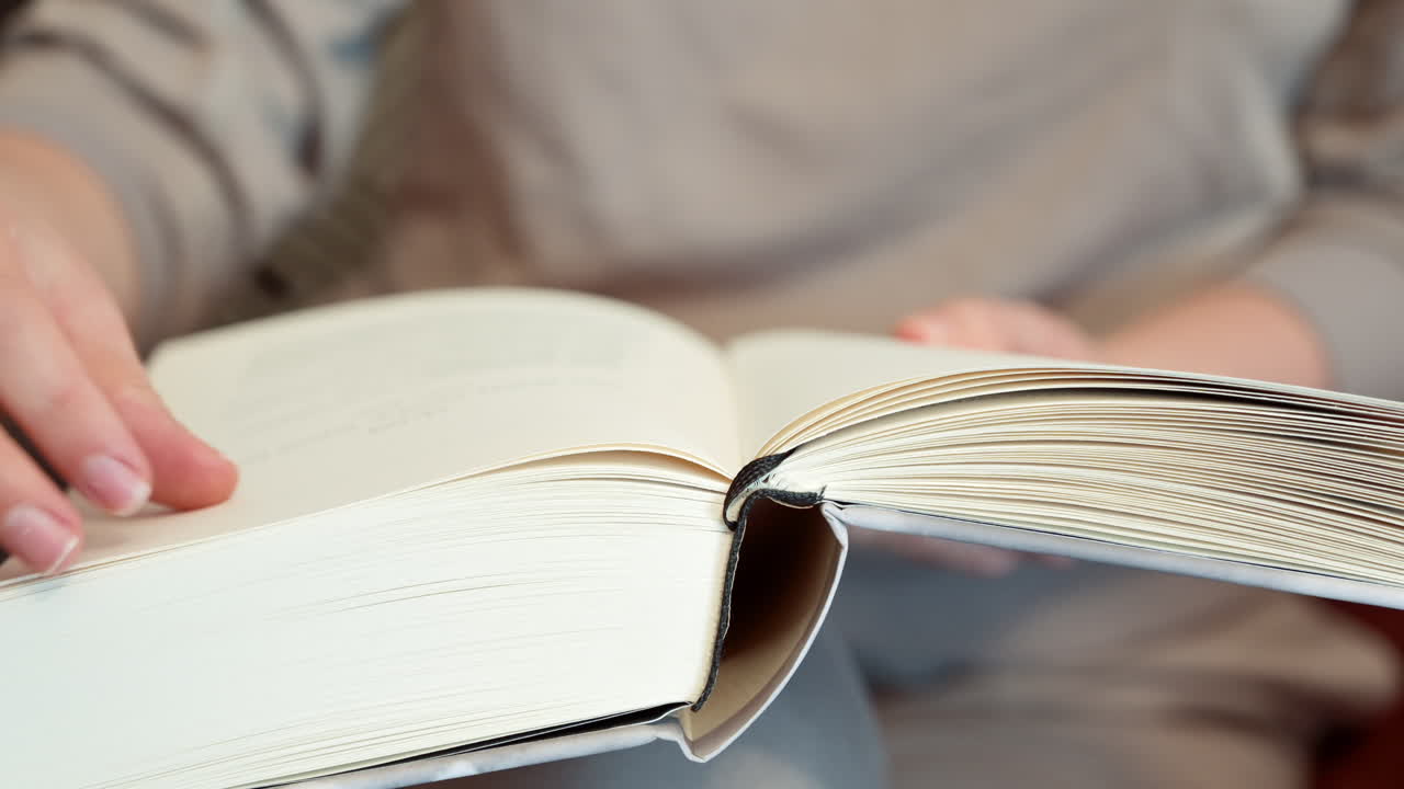 Close up of a woman reading a book at on the couch at home
