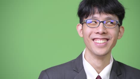 young happy asian businessman smiling while thinking