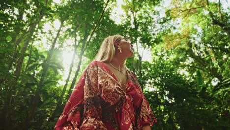 woman in a red dress enjoying the sunlight in a lush tropical forest