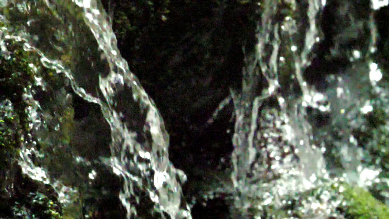 Tight shot of water shot in slow motion as it drops from a mountain waterfall shot at 180 fps
