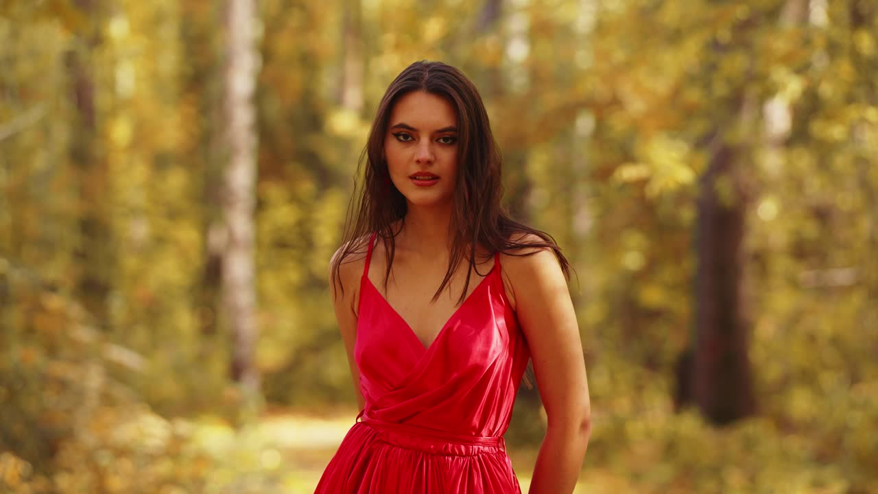 Captivating Elegance: A Woman in a Red Dress Exudes Confidence Amidst a Lush Autumn Forest, Showcasing the Beauty of Nature and Fashion in Perfect Harmony