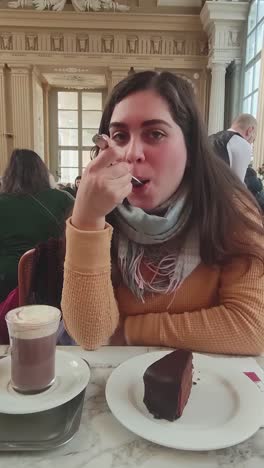 a woman is eating a piece of chocolate cake with a spoon
