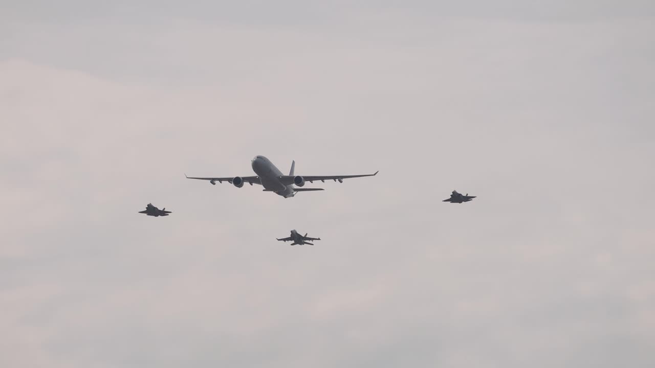 Jets fly in formation with a larger aircraft under overcast skies at the Avalon Airshow in Geelong, Australia