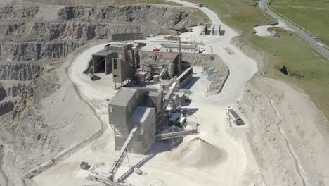 An-aerial-view-of-a-working-asphalt-quarry-building-with-the-quarry-cut-to-the-left-of-frame,-Yorkshire,-UK