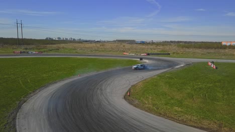 toma aérea de un auto a la deriva a alta velocidad en un giro, hierba verde y una pista de carreras, toma lateral superior