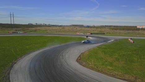 aerial shot of a car drifring on high speed on a turn, green grass and a race track, top side shot