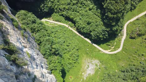 Earial-view-of-the-walking-path-at-the-bottom-of-the-gorge-valley-surrounded-by-karst-limestone-rock-formations-in-Wulong-National-Park,-China
