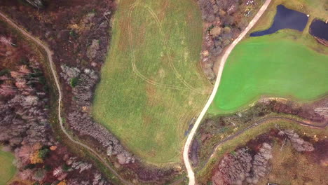 aerial shot going through the cloud,fully covering the frame and afterwards revealing old family home in countryside between trees with cars in the yard - sliding from left to right