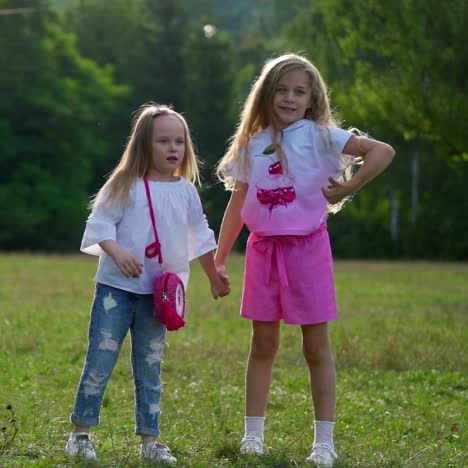 two small cute girls jump cheerfully outdoor in park. happy friends outside hold hands while spending time on fresh air. happy weekend concept