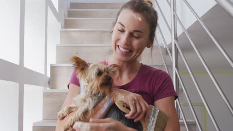 Portrait-of-a-Caucasian-woman-in-quarantine-during-coronavirus-pandemic,-holding-her-dog