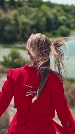 Long haired woman on the natural summer background. Beautiful young lady walking down the hill to the river in a sunny day. Slow motion. Vertical video