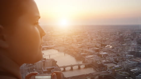 tourist taking photograph of sunset in london skyline  view from the shard