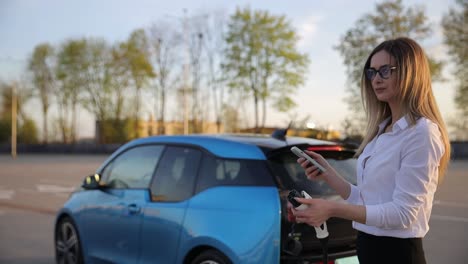 woman is plugging electric vehicle for charging car battery at parking. close up. charging electric car. ev car connected to charger