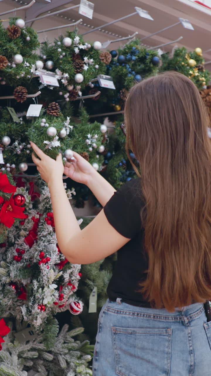 vista lateral de un comprador navegando a través de guirnaldas de navidad bellamente decoradas adornadas con adornos, piñas y elementos festivos en una tienda minorista