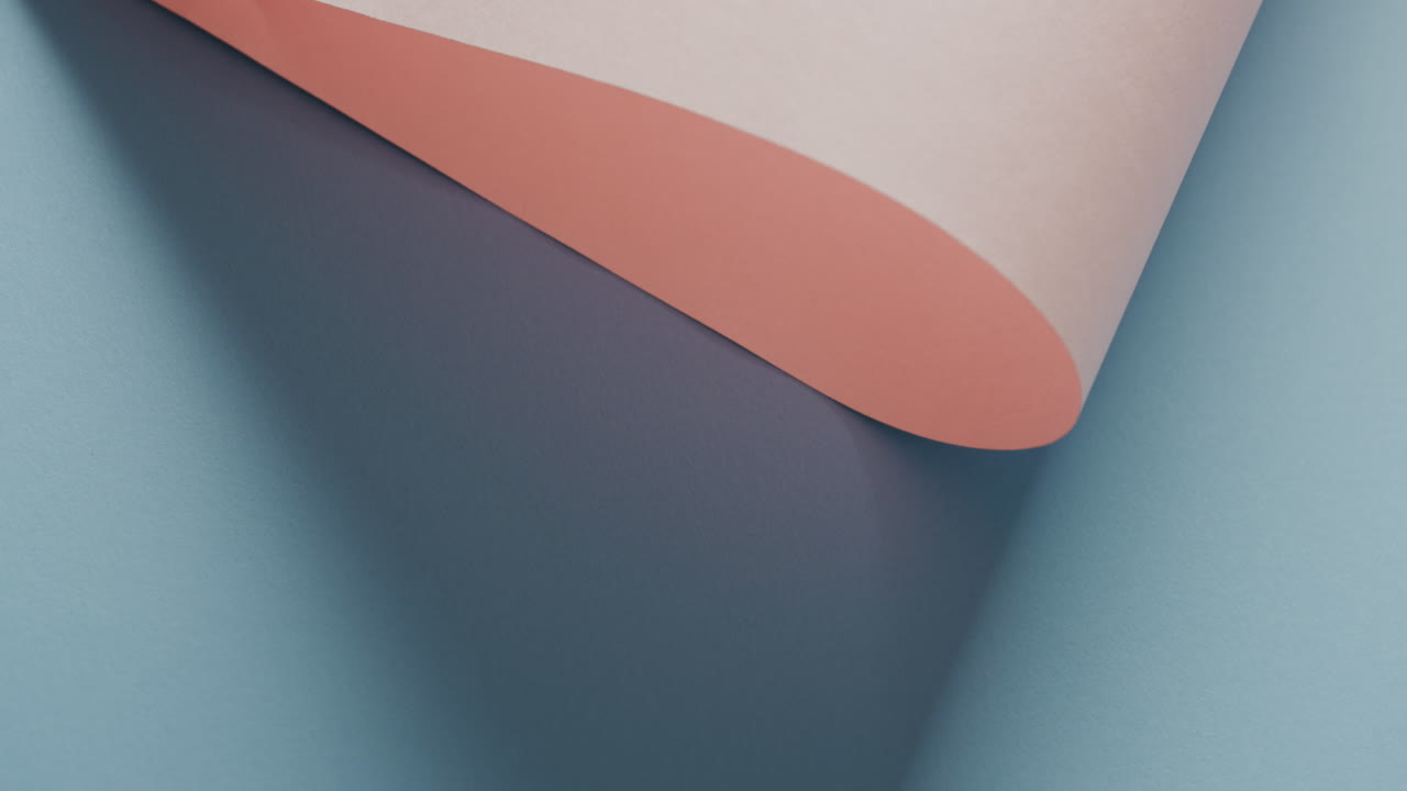 Close up of pink rolled paper on blue background with shadow and copy space in slow motion