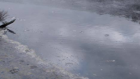 close up of surface of water in sulphuric hot spring lake with atmospheric clouds of misty steam