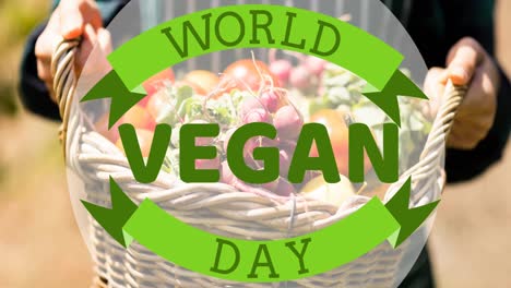 animation of world vegan day text in green over person holding basket of fresh vegetables outdoors