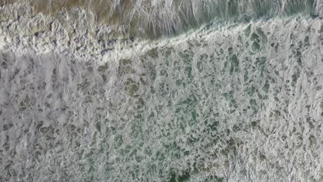 Toma-Aérea-Cenital-Mirando-Hacia-Abajo-A-Las-Olas-Rompientes-Y-Al-Surf-En-Sudáfrica