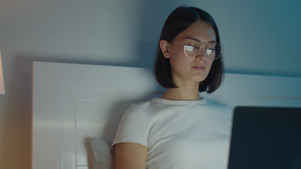 Woman Using Laptop in Bedroom in Evening