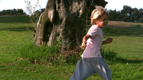 girl child running around after a large tree