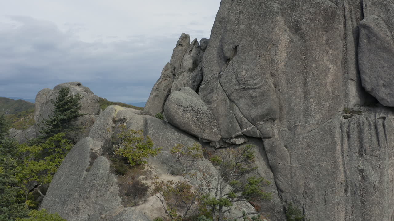 흐린 날 바위 산 절벽 가장자리에 누워 있는 거대한 고대 거석 돌 주위에 공중 피벗 샷