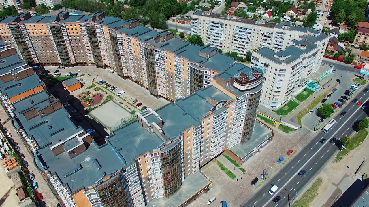 Afordable apartment buildings in the city. Tall skyscrapers with colorful facades with parking space for cars and a children playground in the yard. Aerial view.