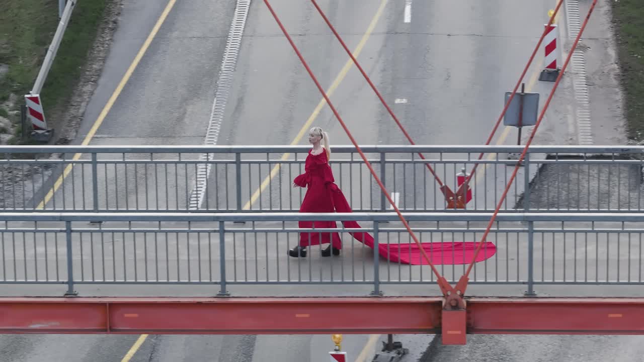 воздушный снимок человека, идущего в ярко-красном платье, идущего через мост