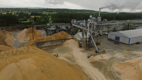 loader hauling heap of sawdust at lumber factory in braskereidfoss, norway