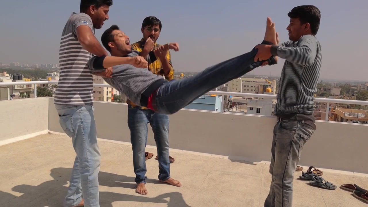 Friends giving birthday bumps or throwing in air during birthday celebration on the rooftop.