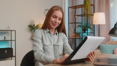 feliz mujer de negocios madura independiente analizando documentos de gráficos sentada en la mesa de la oficina de casa