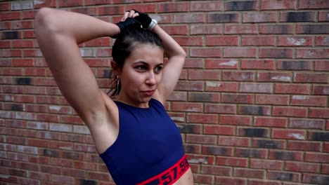 young female fitness caucasian woman fixing long black hair before starting morning routine workout in professional gym