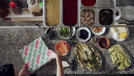 cook preparing pizza for delivery on kitchen