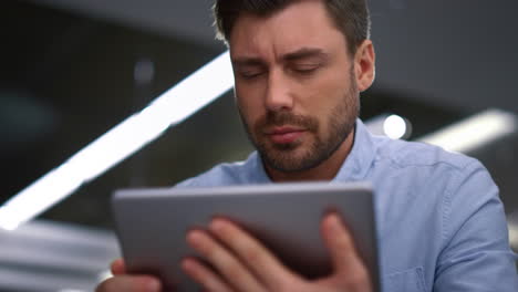 Handsome-businessman-working-tablet-researching-corporate-software-in-office.