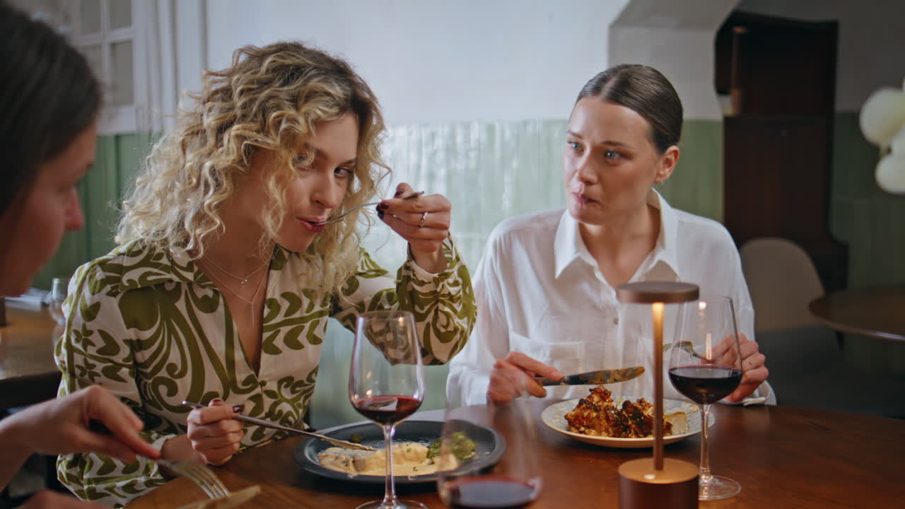 Women enjoy friendly lunch eating delicious food in modern cafe closeup