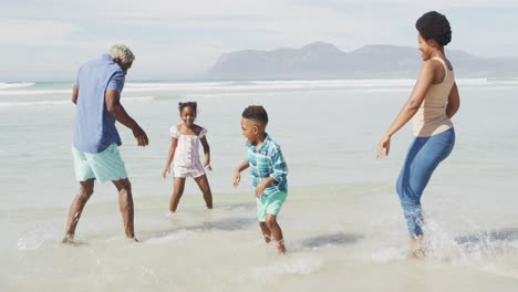 Glückliches-Afroamerikanisches-Paar,-Das-Mit-Kindern-Am-Sonnigen-Strand-Spielt