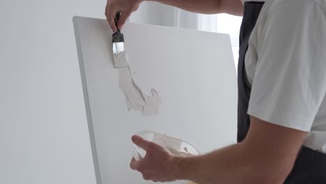 the artist creates a picture on a white canvas using plaster creating an abstract picture - the artist creates a picture on a white canvas using plaster. the process of creating an abstract painting by an artist