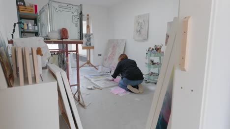 female artist working on a canvas on the floor in home studio