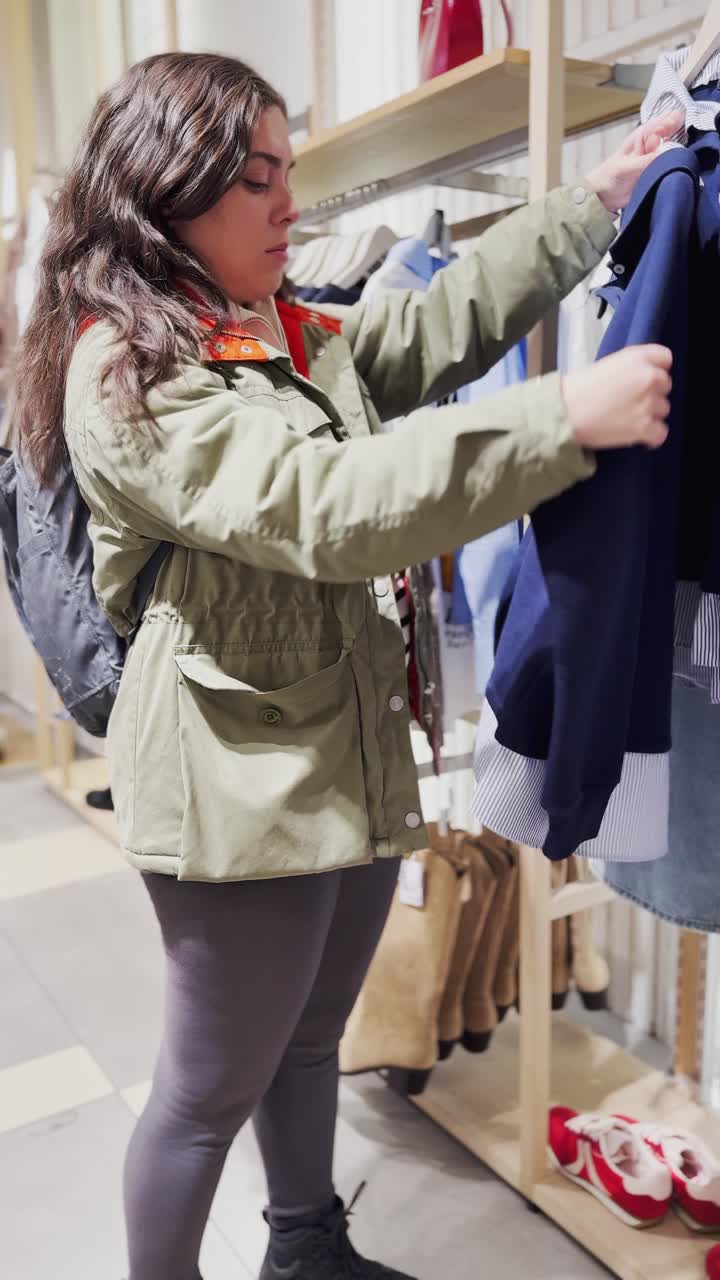 Young woman choosing clothes in fashion store