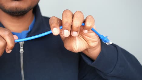 person holding a blue ethernet cable