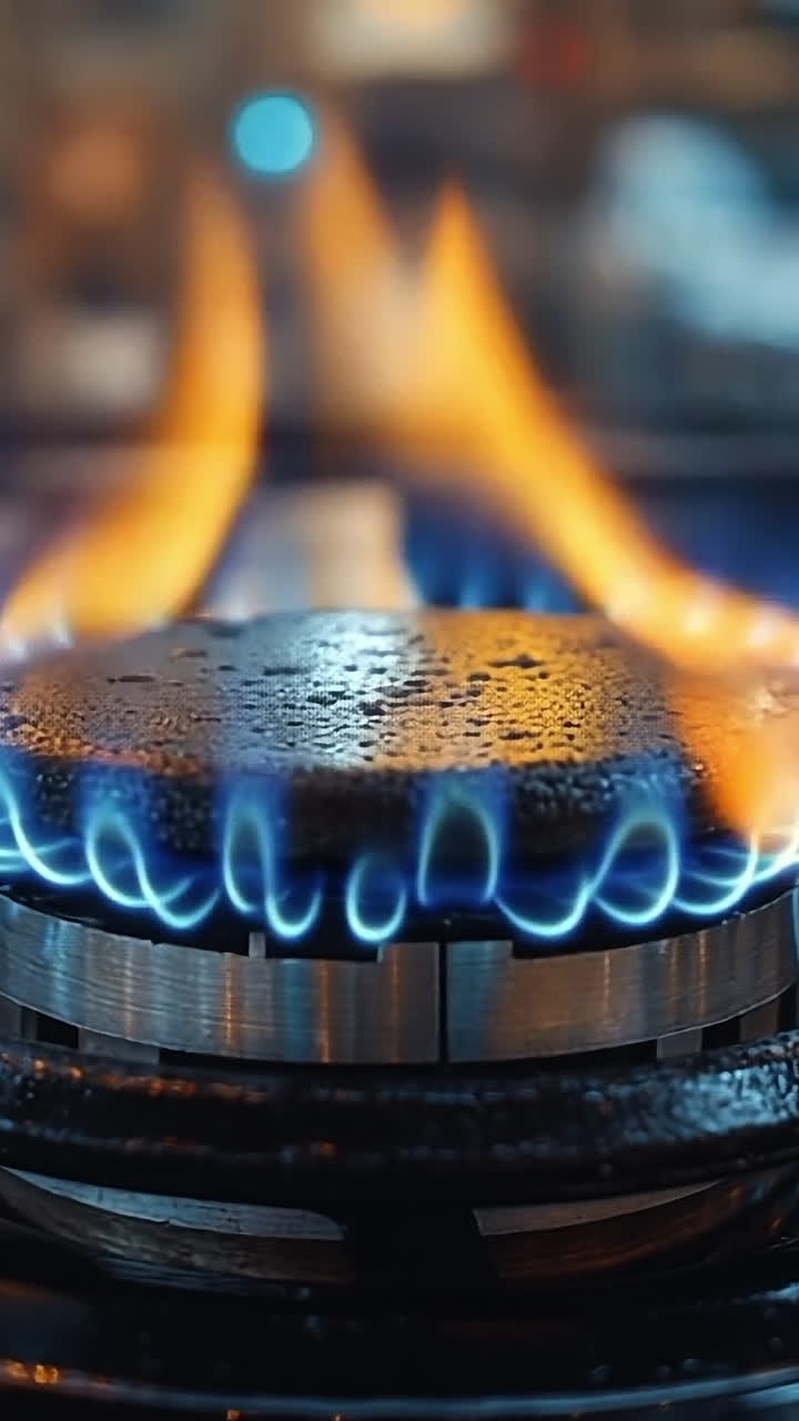 Gas burner with blue flame in kitchen. A gas burner is lit, producing a vibrant blue flame in a modern kitchen setting, highlighting the cooking process.
